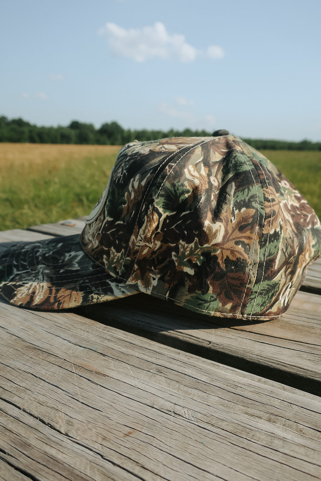 Camouflage-patterned cap on a wooden surface with a natural background - otto style cap
